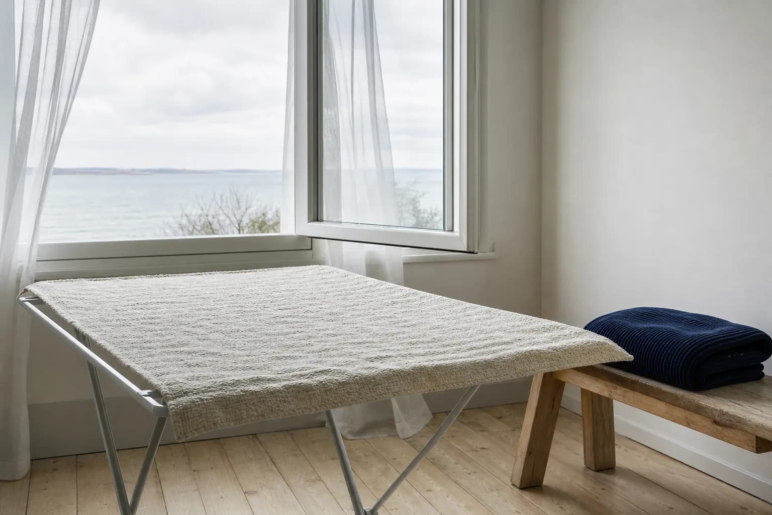 En ljus textil som torkar med brett stöd vid ett öppet fönster.